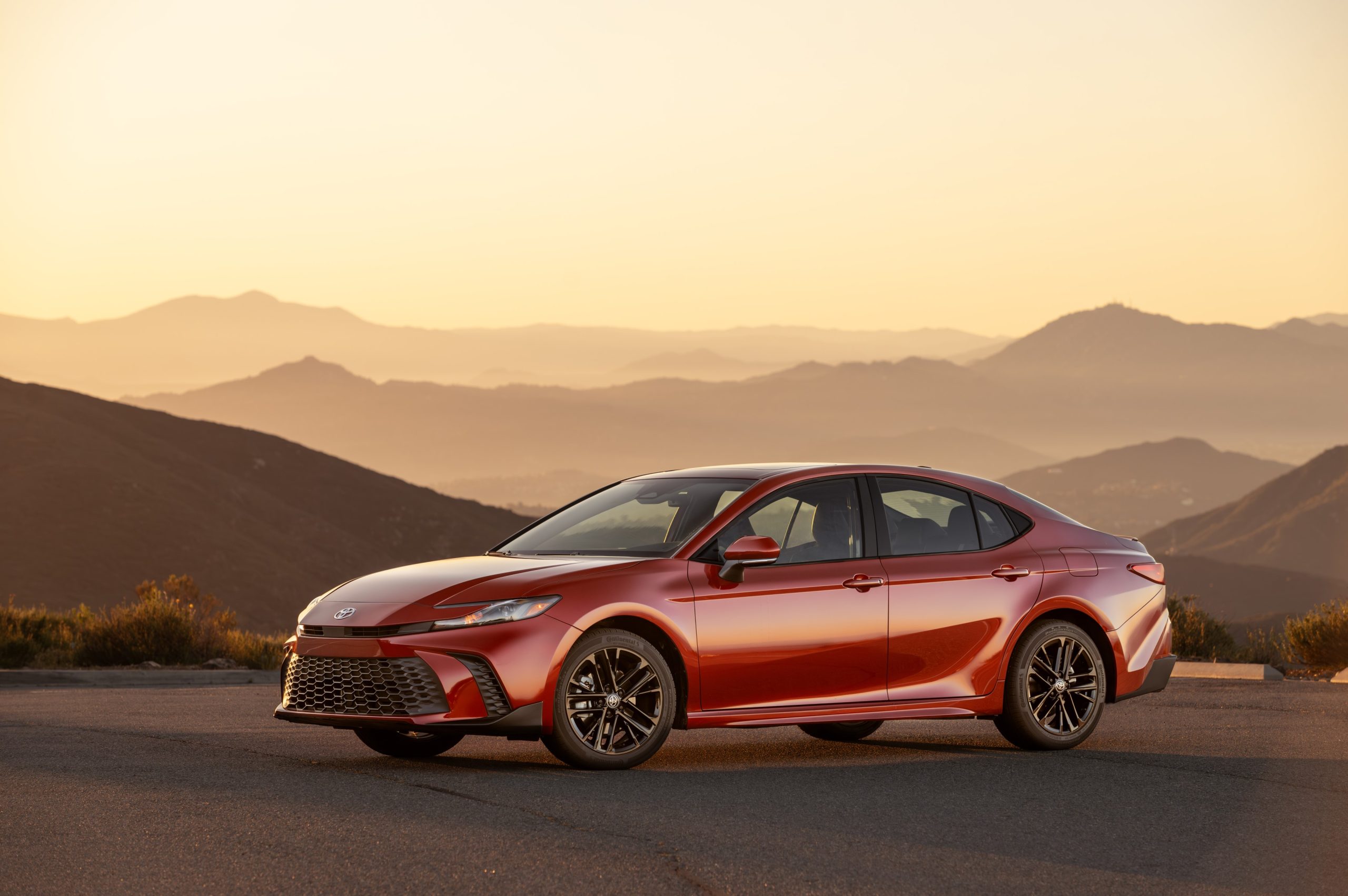 Red 2026 Toyota Camry parked in front of scenic mountain backdrop highlighting sleek design