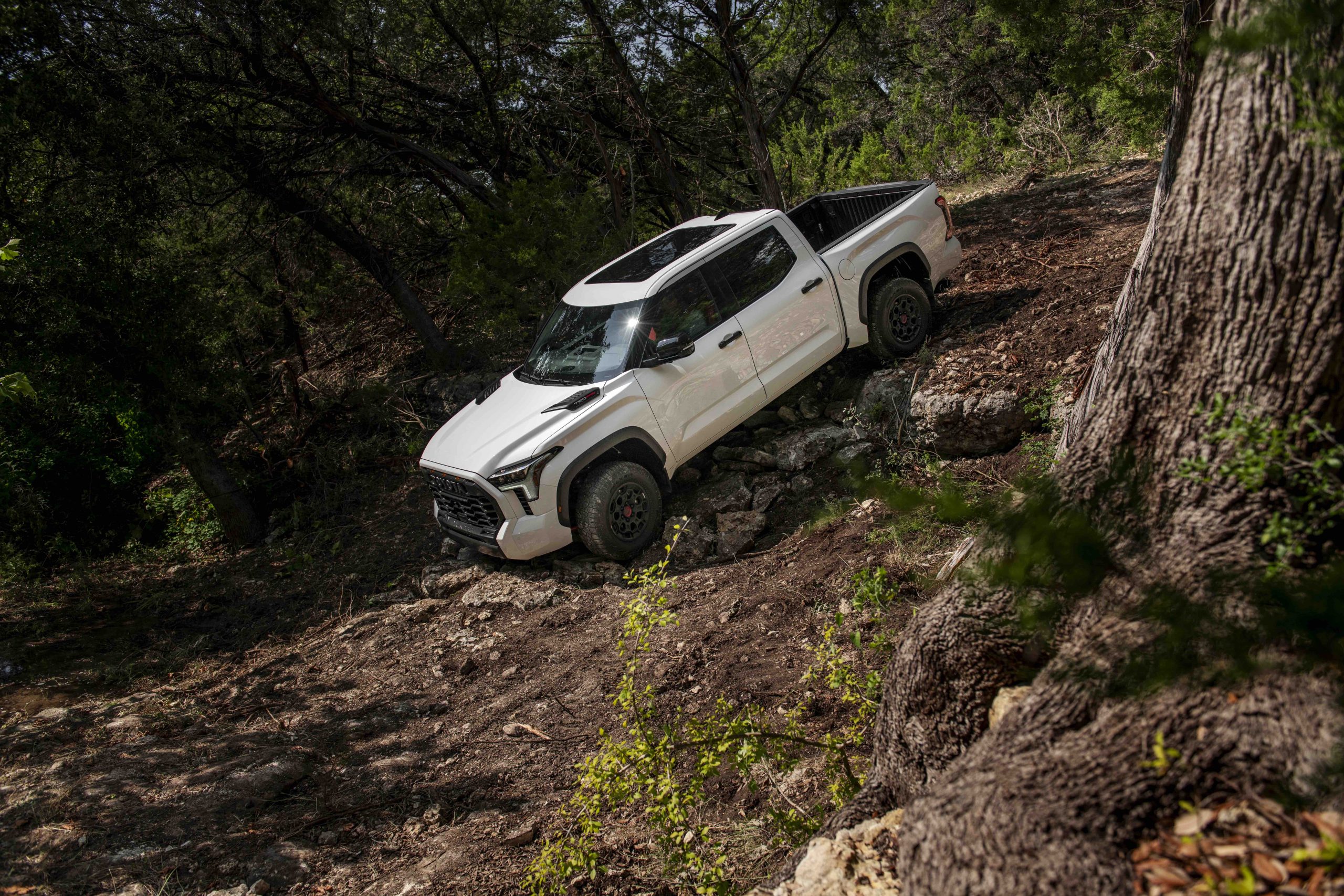 2026 Toyota Tundra White Hybrid driving down a rocky terrain
