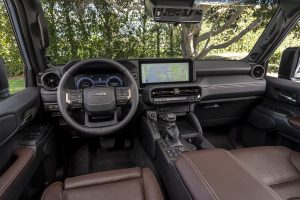 2027 Toyota Land Cruiser interior with multimedia touchscreen display, steering wheel, and premium brown seating