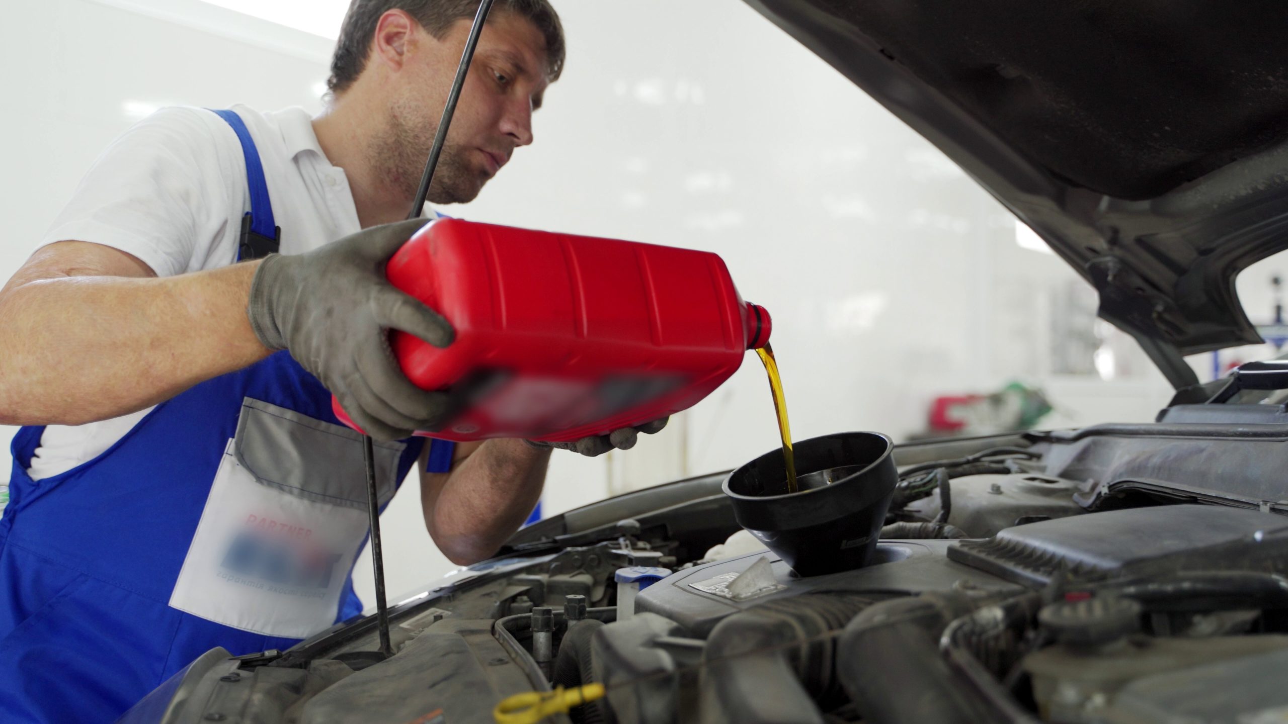 Auto Technician pouring engine oil into engine